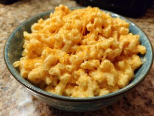 A close-up shot of a bowl filled with creamy 3 ingredient stovetop mac and cheese, topped with shredded cheddar.