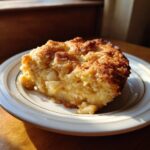 A slice of warm Apple Snickerdoodle Dump Cake on a plate, showing chunks of apple and a crumbly topping.