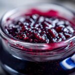 Close-up of a glass jar filled with glistening, homemade Blueberry Jam.