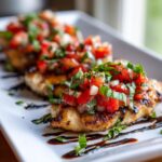 Close-up of grilled Bruschetta chicken fillets topped with fresh tomato, basil, and onion salsa, drizzled with balsamic glaze.