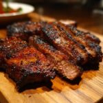 Close-up of perfectly grilled carne asada steak slices, showcasing a rich marinade and juicy interior.