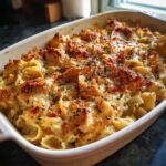 A close-up of a bubbling Chicken Bacon Ranch Casserole in a white baking dish, topped with melted cheese and herbs.