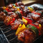 Close-up of juicy honey BBQ chicken kabobs with colorful bell peppers and zucchini on a grill rack.