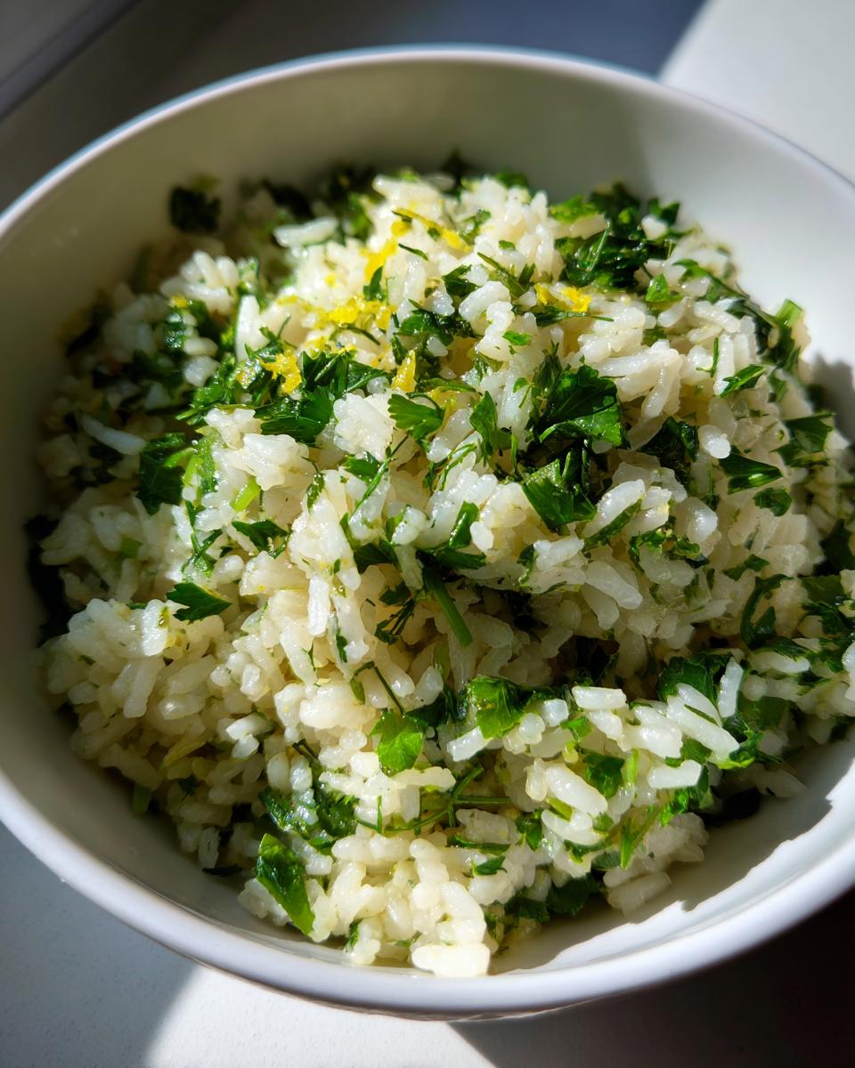 A close-up of fluffy Mediterranean lemon rice generously topped with fresh parsley and lemon zest.