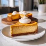 A slice of no bake pumpkin cheesecake topped with whipped cream and cinnamon on a white plate.