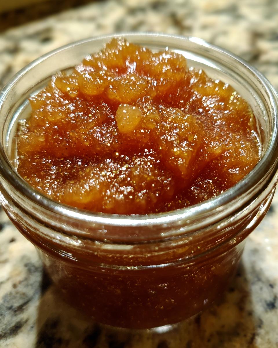 Close-up of a jar filled with glistening, amber-colored old-fashioned pear preserves.
