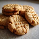 A close-up, mouthwatering stack of classic peanut butter cookies with the signature fork marks.