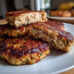 A close-up of a stack of golden brown tuna patties, one cut in half to show the flaky texture inside.