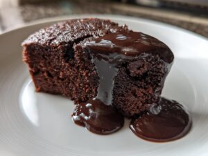 A moist slice of chocolate pudding cake generously topped with rich, glossy chocolate sauce.