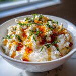 Close-up of a fluffy white ricotta dip drizzled with amber honey and topped with fresh basil.