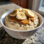 A close-up of creamy banana oatmeal topped with melted peanut butter and fresh banana slices.