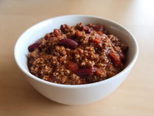 A close-up of a white bowl filled with thick, rich chili featuring ground meat and kidney beans, showcasing the best chili recipe.