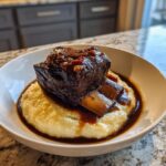 A single, rich, dark braised short ribs served atop creamy polenta with savory sauce.
