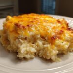 A close-up of a creamy, cheesy serving of rice casserole topped with melted, browned cheddar cheese.