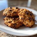 A stack of three textured, oatmeal-based breakfast cookie treats topped with visible chocolate chips.