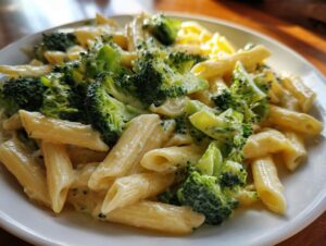 Close-up of creamy broccoli pasta featuring penne noodles coated in a light sauce with bright green broccoli florets.