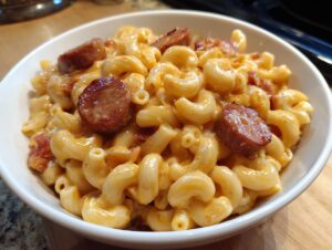 Close-up of creamy macaroni mixed with cheese sauce and topped with slices of browned kielbasa pasta.