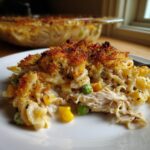 A close-up serving of creamy tuna pasta bake, featuring shredded tuna, peas, and corn, topped with golden brown breadcrumbs.