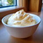 A close-up of thick, creamy homemade mayonnaise piled high in a small white bowl.