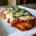 Close-up of a perfectly cooked chicken parmesan recipe cutlet topped with marinara sauce, melted mozzarella, and fresh basil.