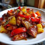 Close-up of glazed chicken pieces mixed with pineapple, red peppers, and onions from the Hawaiian chicken sheet pan.