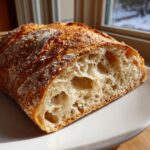 Close-up of the airy, open crumb structure inside a freshly baked Italian bread loaf.