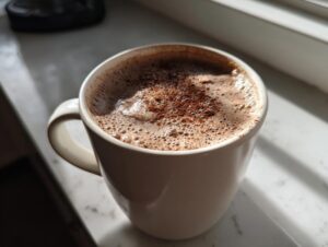 Close-up of a steaming mug of Mexican hot chocolate topped with foam and cinnamon.