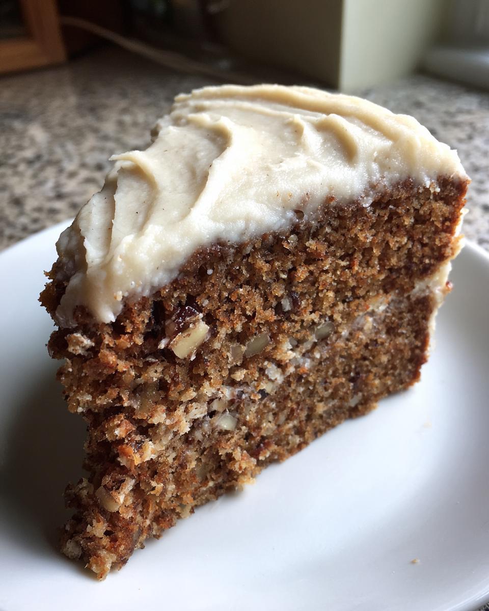 Close-up of a moist slice of applesauce cake topped with thick cream cheese frosting.