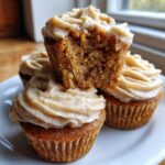 Close-up of moist banana cupcakes stacked, showing the crumb texture and creamy cinnamon frosting.