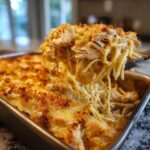 A spoonful of creamy monterey chicken spaghetti being lifted from a baking dish topped with golden brown breadcrumbs.