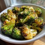Close-up of crispy, roasted smashed broccoli florets seasoned with cheese and spices in a white bowl.