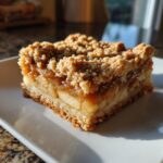 A single serving of delicious apple pie bars with a thick layer of cinnamon apple filling and a crumbly streusel topping.