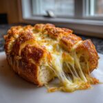 Close-up of baked cheese bread with extreme cheese pull, showing gooey melted cheese strings.