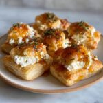 Close-up of flaky puff pastry squares topped with creamy goat cheese and drizzled with honey, garnished with thyme for amazing goat cheese and honey bites.