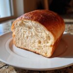 Close-up of a freshly baked loaf of whole wheat bread, showing a soft, airy crumb and golden-brown crust.