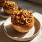 A close-up of one delicious baked apples dessert topped high with a crunchy oat and brown sugar crumble.