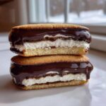 Two delicious boston cream pie cookies stacked, showing the vanilla cream filling and rich chocolate ganache topping.