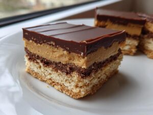 A square slice of buckeye graham crackers dessert showing layers of graham cracker base, chocolate, peanut butter filling, and chocolate topping.