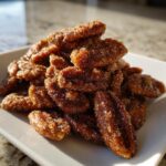 A close-up pile of freshly made candied pecans recipe nuts coated in sparkling sugar crystals.