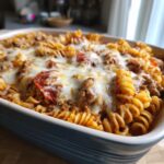Close-up of a baked pizza pasta casserole with rotini pasta, meat sauce, pepperoni, and melted mozzarella cheese.