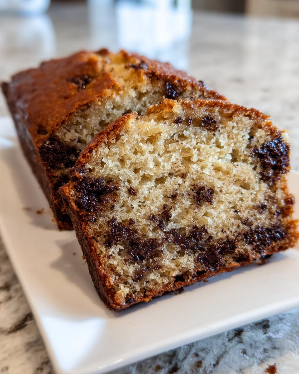Close-up of a loaf of moist chocolate chip banana bread, sliced to show the interior texture and melted chips.