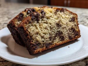 Two moist slices of chocolate chip banana bread recipe showing melted chocolate chips and a golden crust.