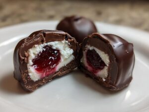 Close-up of a chocolate covered cherries candy cut in half, showing the creamy filling and cherry center.