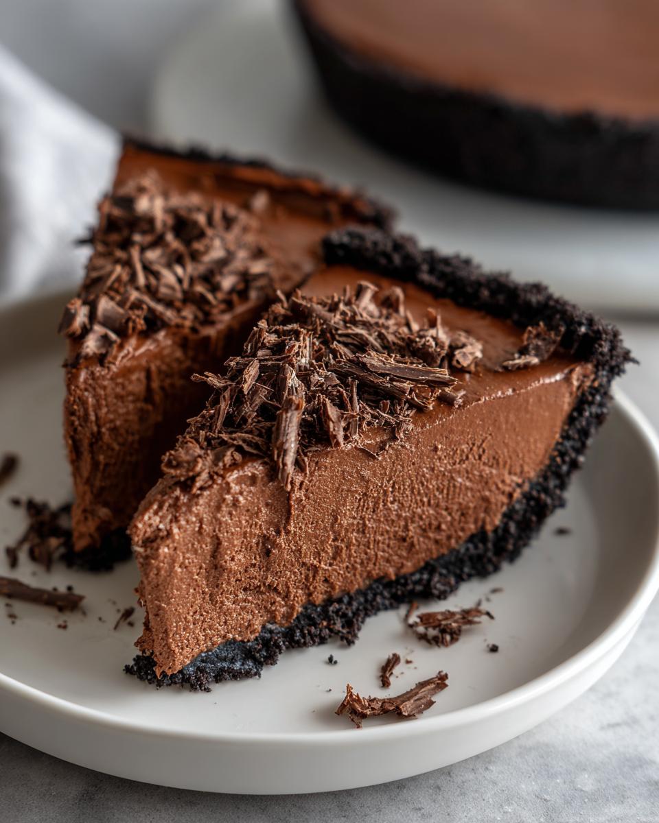 Two slices of rich chocolate mousse pie with a dark crust, topped generously with chocolate shavings.