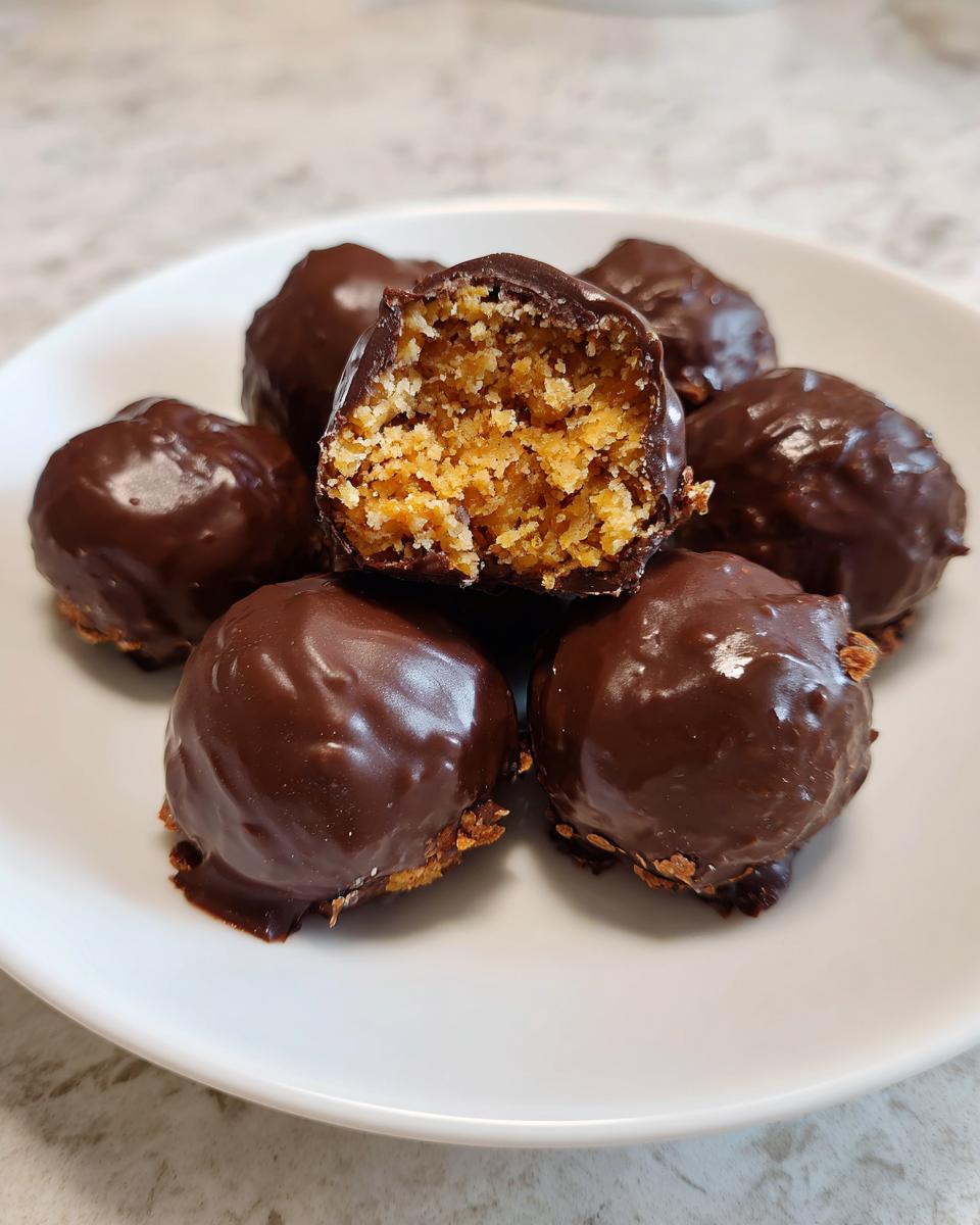 A plate of chocolate-covered pecan pie balls, one cut in half showing the textured, sweet interior.