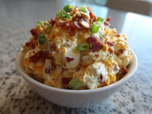 A close-up of a creamy, cheesy Neiman Marcus dip topped with bacon bits, green onions, and chopped nuts.