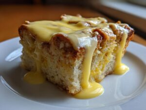 A close-up of a square slice of eggs benedict casserole topped generously with dripping hollandaise sauce.