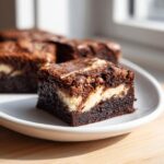 A close-up of a fudgy cream cheese brownies square showing the dark chocolate base and white cream cheese swirl.