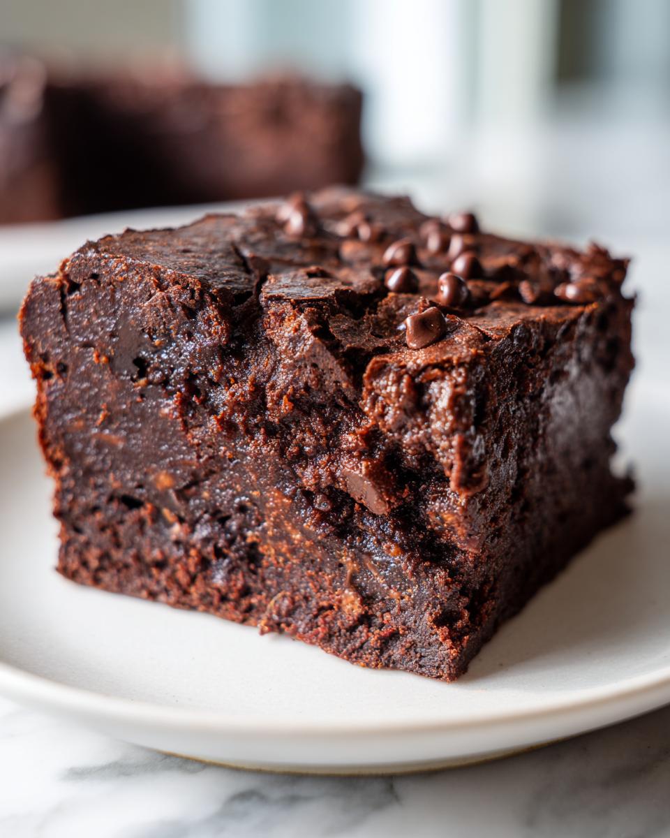 Close-up of a rich, fudgy slice of date brownies topped with mini chocolate chips.