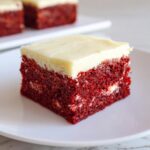 Close-up of a fudgy red velvet brownies square topped with thick cream cheese frosting.